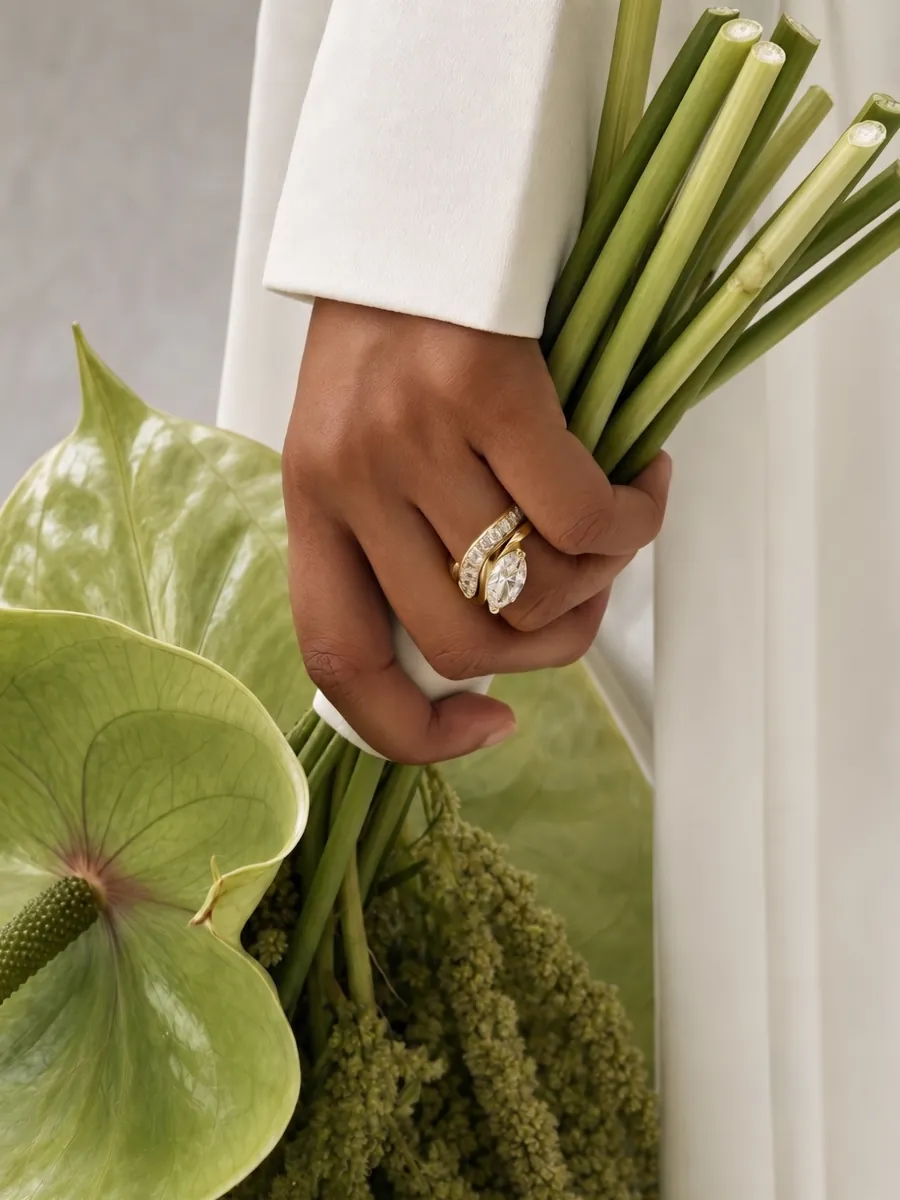 Hand holding a bouquet, wearing a marquise ring